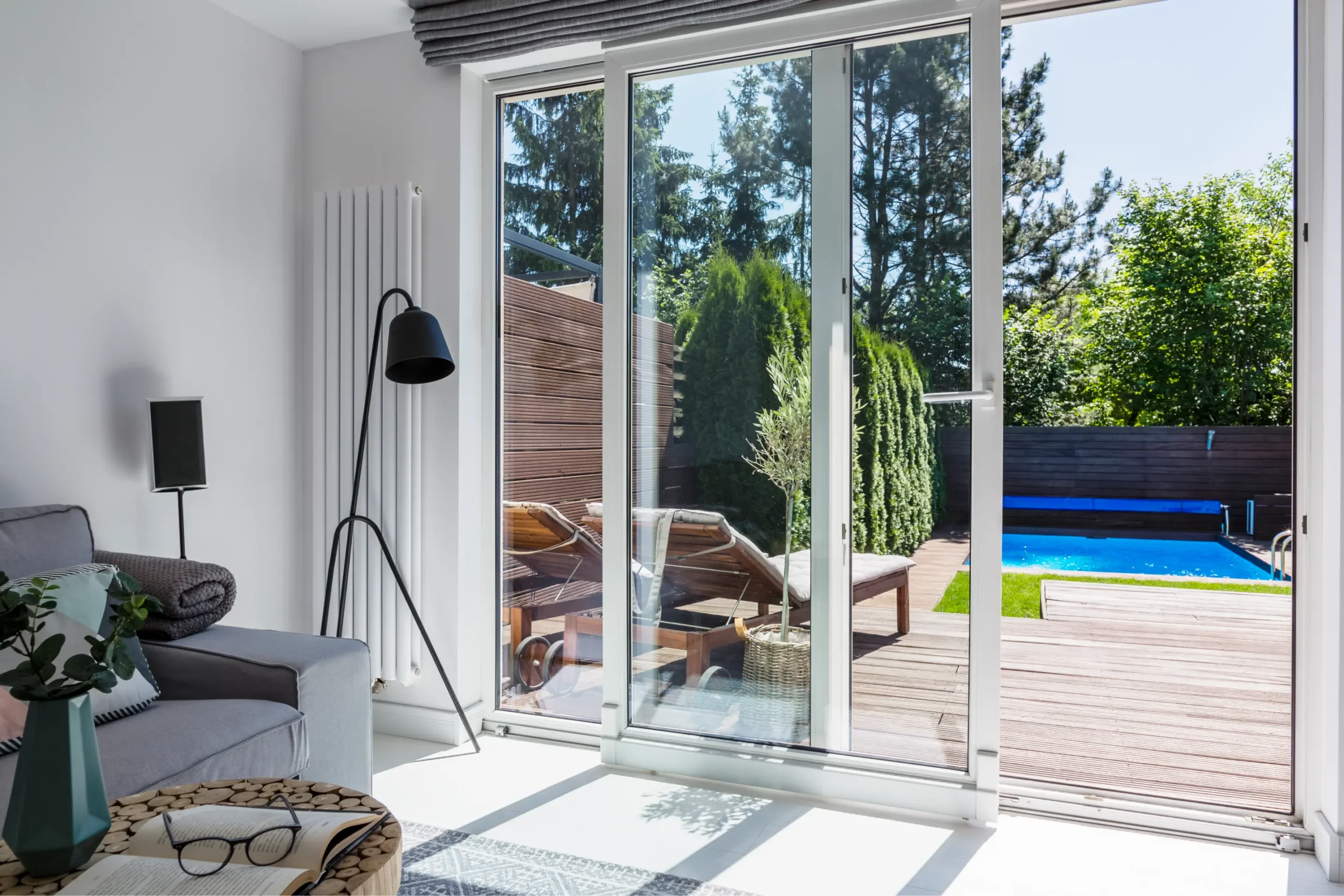 Bright living room featuring sliding glass doors opening to a backyard; highlighting The Glass House's expertise in various glass installations, including showers, mirrors, and more.