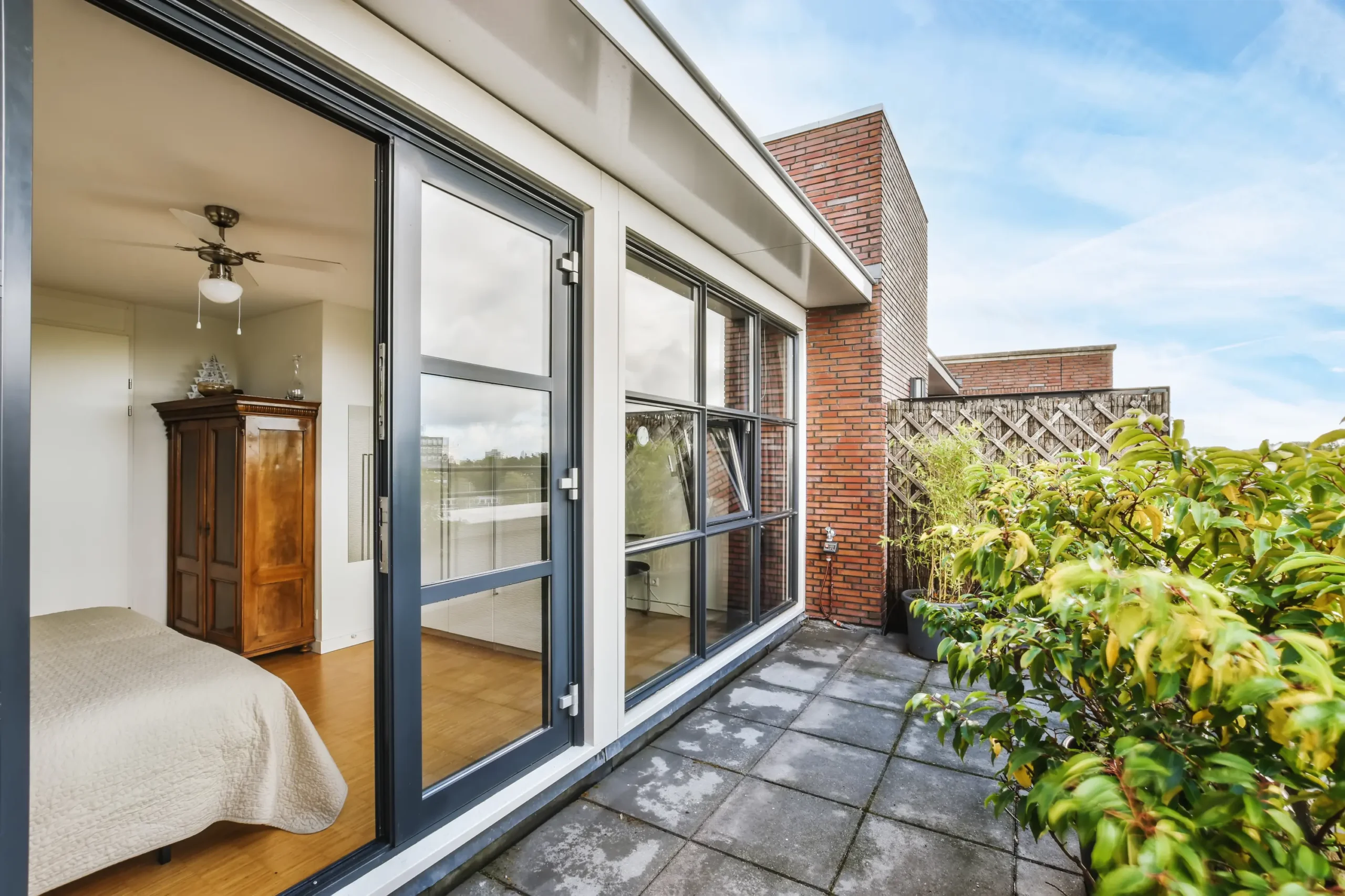 Exterior view of a contemporary home featuring large glass doors leading to a patio; highlighting The Glass House's local expertise serving Bourne and Cape Cod.
