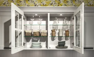 Open kitchen cabinet showcasing stylish glass shelves, neatly organized with dishes and glassware, maximizing visibility and light.