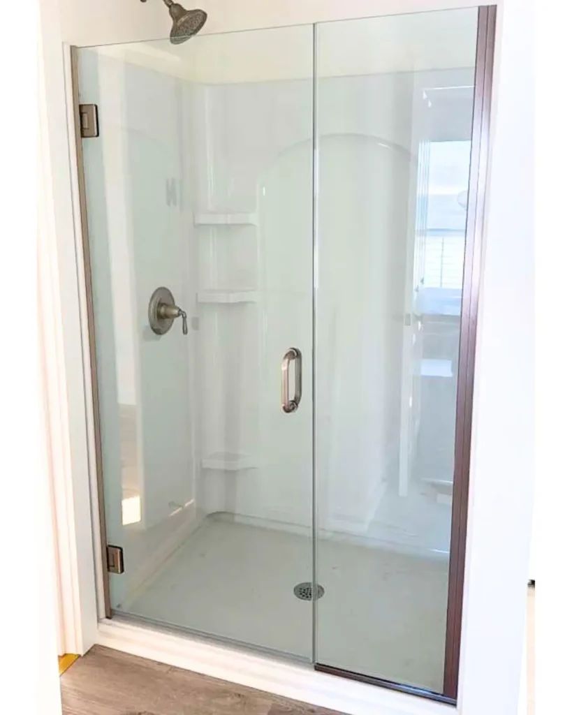 Custom glass shower door enclosure with bronze hardware installed in Orleans MA
