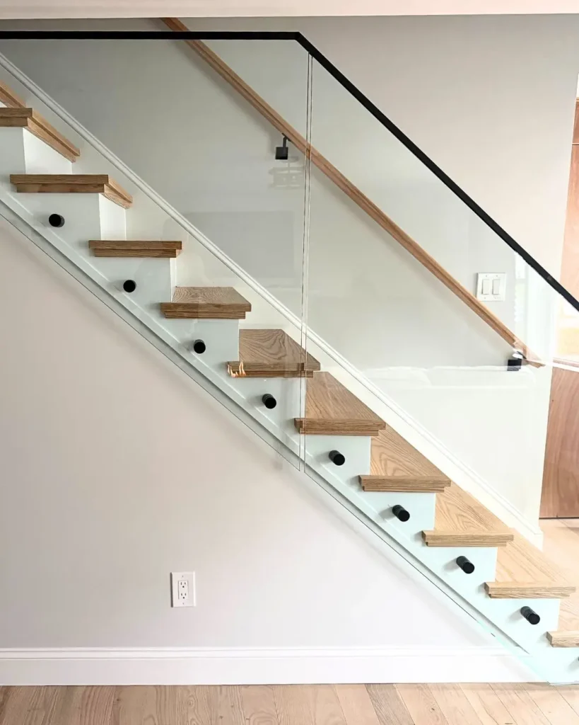 Custom frameless glass stair railing with black standoff hardware installed in Hyannis MA
